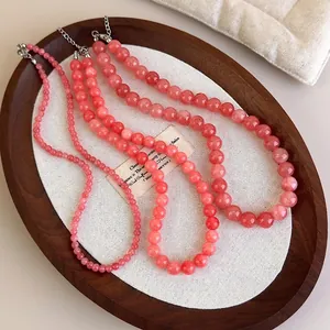 Collier élégant en pierres naturelles roses avec chaîne ajustable sur plateau en bois