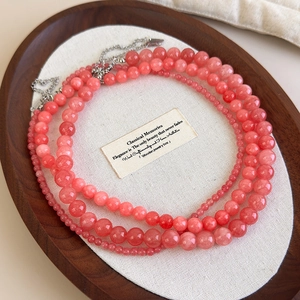 Colliers en perles de pierre naturelle rose sur plateau bois, bijoux en cristal élégants