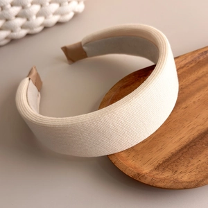 Detail of cream-colored knitted sponge headband showing the ribbed fabric texture