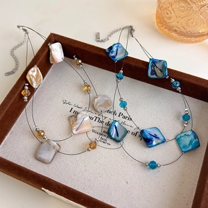 Detailed macro view of layered shell necklaces with faceted beads on a vintage brown tray
