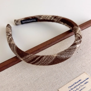 Detailed macro view of the handmade label and brown plaid fabric texture on a padded headband