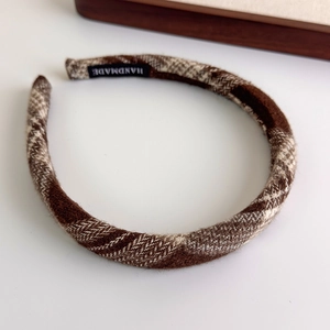 Close-up of handmade brown checkered fabric headband with wool-like texture and inner label