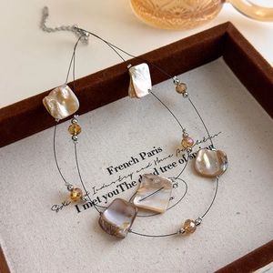 Detail of double-layer necklace featuring natural shell slices and amber beads on linen tray