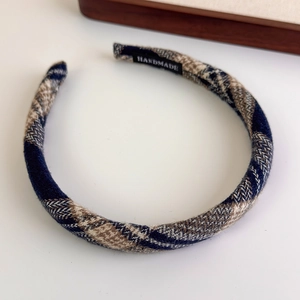 Detailed macro view of plaid fabric headband featuring handmade woven label on inner side