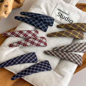Close-up of checkered fabric hair clips set on a rustic cotton bag and wooden tray