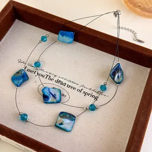 Detail of double-layer beaded necklace with blue irregular shells and silver lobster clasp