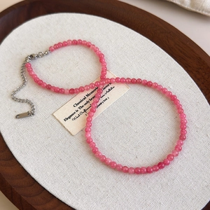 Gros plan du collier en perles de pierre rose avec fermoir mousqueton argenté et chaîne