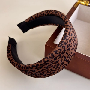 Detailed side view of vintage leopard print padded headband on a wooden stand