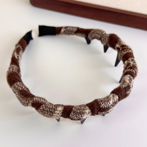 Detail view of brown plaid fabric headband with non-slip inner teeth and soft texture