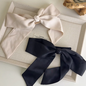 Detailed macro view of large satin bow hair clips in elegant black and beige colors