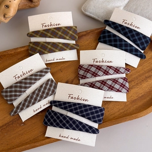 Detail view of handmade plaid fabric hair clips set on a wooden display tray