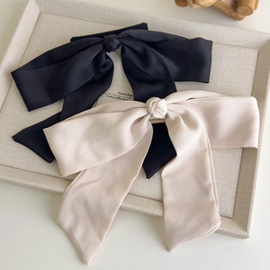 Elegant set of black and champagne satin bow hair clips on a linen jewelry tray