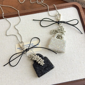 Elegant crystal mini bag pendant necklace in black and silver finishes on a wooden tray