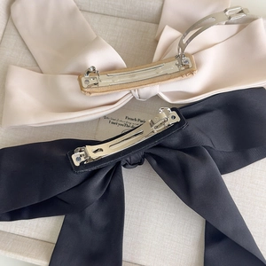 Detail view of the metal spring clip mechanism on elegant satin bow hair accessories