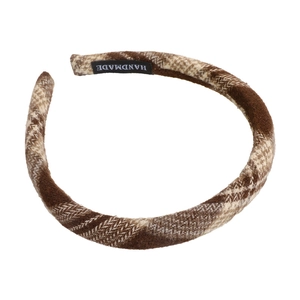 Detailed view of the brown plaid fabric texture and handmade label on the headband