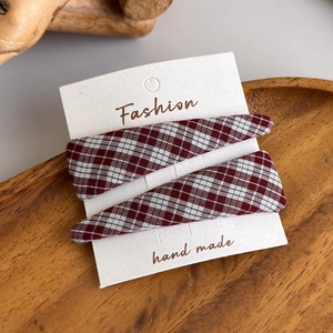 Close-up of red and white checkered fabric BB hair clips on a decorative wooden tray