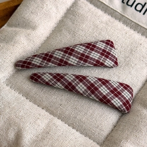 Close-up of red and white plaid fabric hair clips set on a beige quilted background