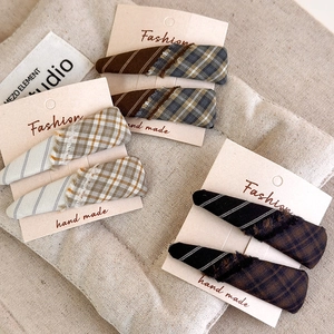 Detailed set of plaid fringed fabric hair clips in earthy tones on a display card