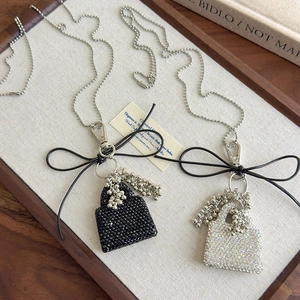 Close-up of sparkling rhinestone mini handbag pendants with ribbon bows and bead chains