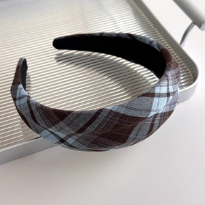 Detailed macro of vintage plaid fabric headband with brown and blue patterns on silver tray