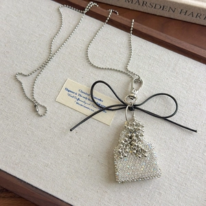 Close-up of sparkling rhinestone bag pendant with black bow on long silver ball chain