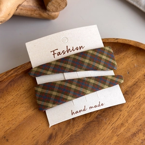 Close-up of retro plaid fabric hair clips in autumn tones on a wooden display tray