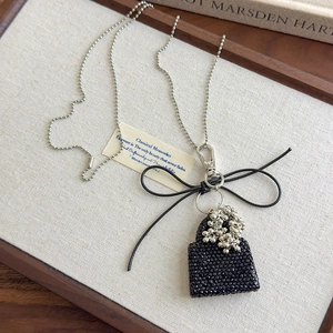 Close-up of sparkling black rhinestone bag pendant necklace with elegant black bow decoration