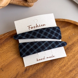 Detailed close-up of blue and black plaid fabric hair clips on a wooden tray