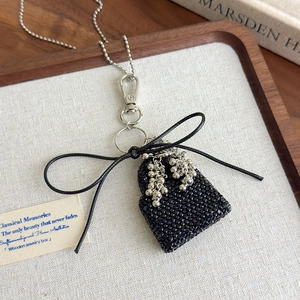 Close-up of elegant black beaded handbag pendant with silver tassel and lobster clasp detail