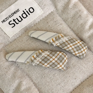 Detail view of plaid fringe fabric hair clips with minimalist beige and brown stitching