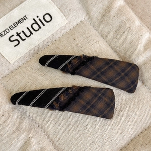 Detailed view of two plaid fabric patchwork hair clips with cozy brown plush texture