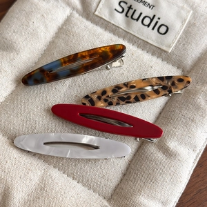 Detail of tortoise shell and marble acetate oval hair clips on a quilted fabric pouch