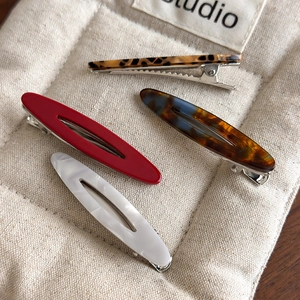 Detailed macro view of acetate hair clips in marble, amber, and leopard print textures