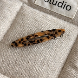 Close-up of a tortoiseshell acetate hair clip with a silver metal alligator clasp detail