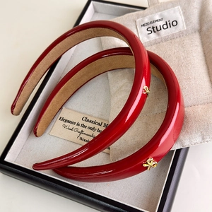 Retro red PU leather headband set with gold bow charms on a dark display background