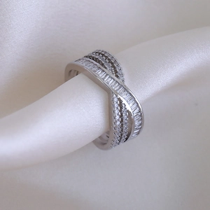 Macro detail of intertwined silver ring with baguette and round cut cubic zirconia stones