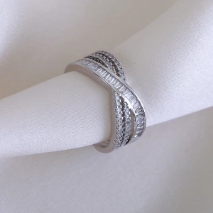 Detailed macro view of crisscross luxury silver ring with zircon stones on silk