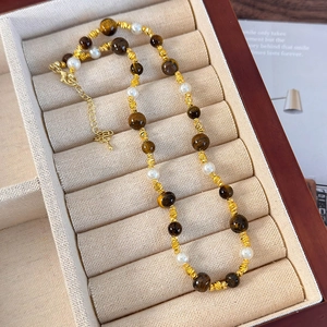 Détail d'un collier en perles et œil de tigre avec fermoir mousqueton et chaîne réglable