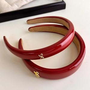 Detail of red patent leather headbands with gold bow accents and non-slip lining