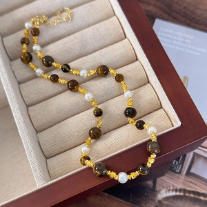 Détail du collier de perles et d'oeil de tigre présenté dans un écrin à bijoux en velours