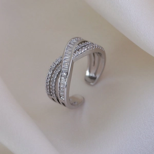 Detail of silver crossover ring featuring baguette and round-cut cubic zirconia stones