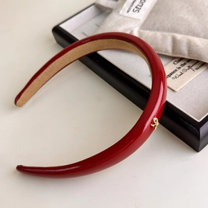 Macro detail of dark red PU leather headband with a gold bow buckle and velvet lining