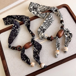 Detail view of paisley silk scarves with wooden beads and marble resin necklace accessories