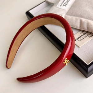 Detail showing red PU leather headband with gold bow clasp and non-slip inner lining