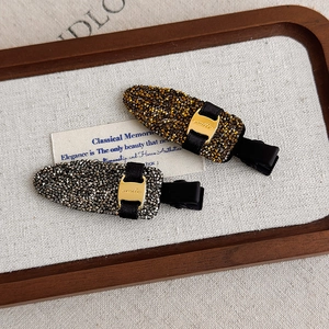 Détail de barrettes à strass de luxe avec boucles dorées 'smile' sur un plateau vintage