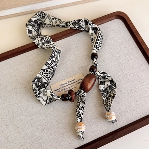 Close-up of vintage paisley fabric necklace with handcrafted dark wooden beads detail
