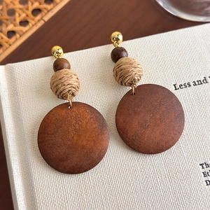Detail of bohemian wood earrings with woven spheres and metal studs on white book