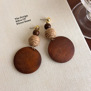 Detailed close-up of Bohemian geometric wooden drop earrings on a minimalist book cover
