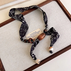Detail view of retro paisley fabric ribbon and wood bead necklace on vintage board