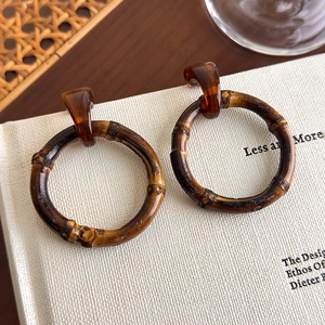 Detailed view of bamboo-style wooden hoop earrings with amber resin connector on a book